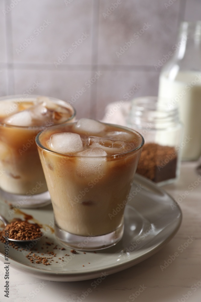 Refreshing iced coffee with milk in glasses, ingredients and spoon on light table, closeup Refreshing iced coffee with milk in glasses, ingredients and spoon on light table, closeup