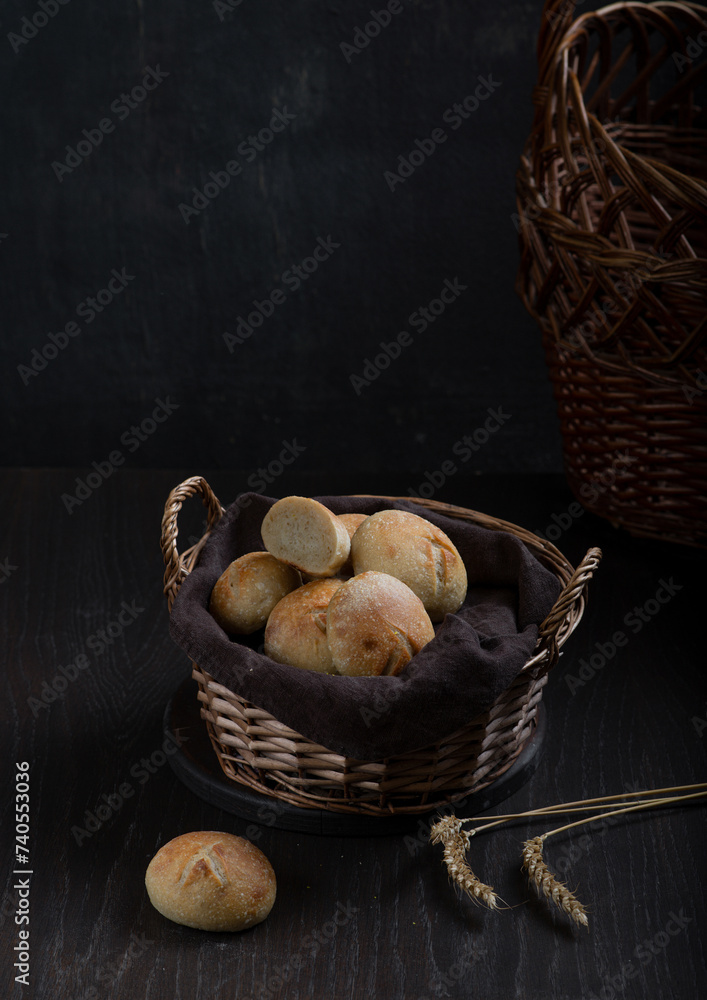 Homemade wheat buns in a basket on a dark background