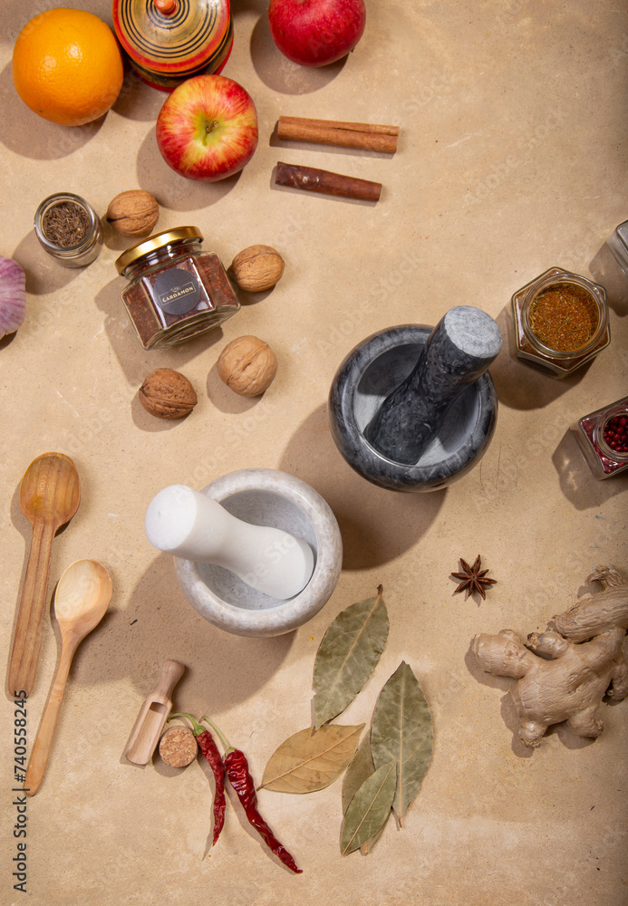 Marble mortars for grinding spices among spices and products on a beige background