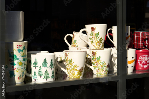 White and red mugs with various designs in a small shop window with a black background. photo