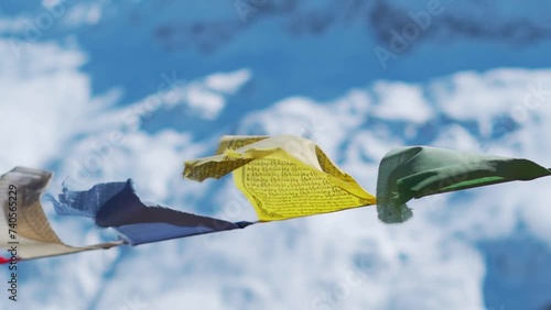 Slow motion shot of prayer flags waving in the wind in front of snowy Himalayan mountain peaks during the winter season as seen from Sissu at Lahaul Valley in Himachal Pradesh, India after snowfall.