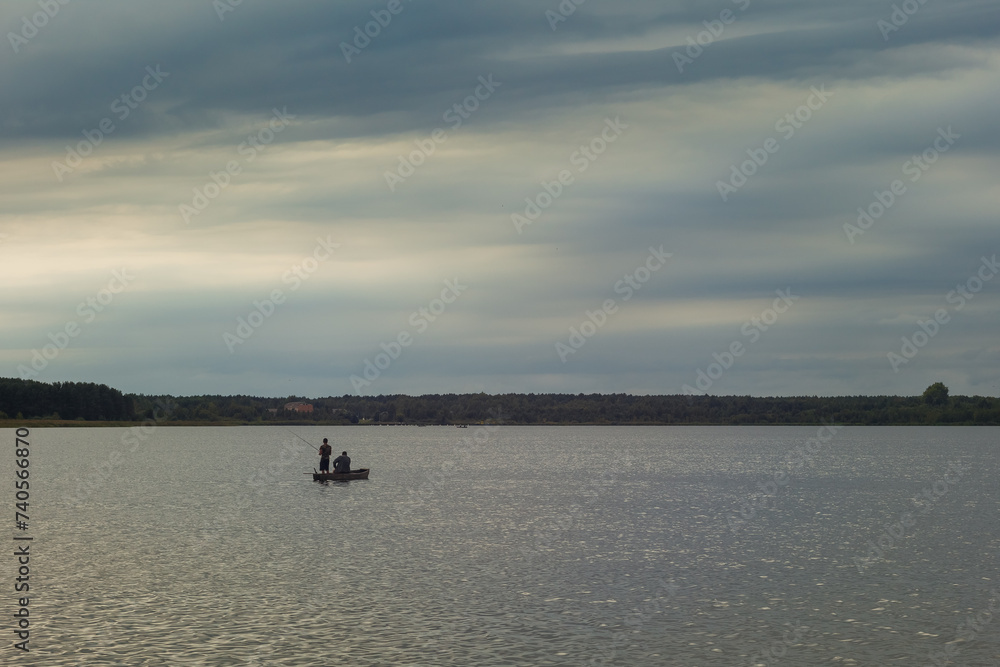View on the opposite bank of the lake. Fishermen on a boat Small waves on the surface of the water. 