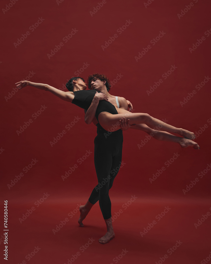Obraz premium Beautiful, elegant young woman and handsome man, ballet dancer dancing against red background. Black and red. Concept of classic art, aesthetics, emotions, ballet dance, talent