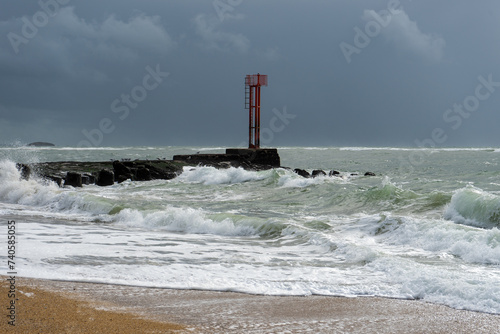 La barre d'Etel, en Bretagne, se dresse sous un ciel menaçant tandis que l'océan agité gronde. Dans cette scène saisissante, la nature déchaînée de la côte bretonne prend vie.
