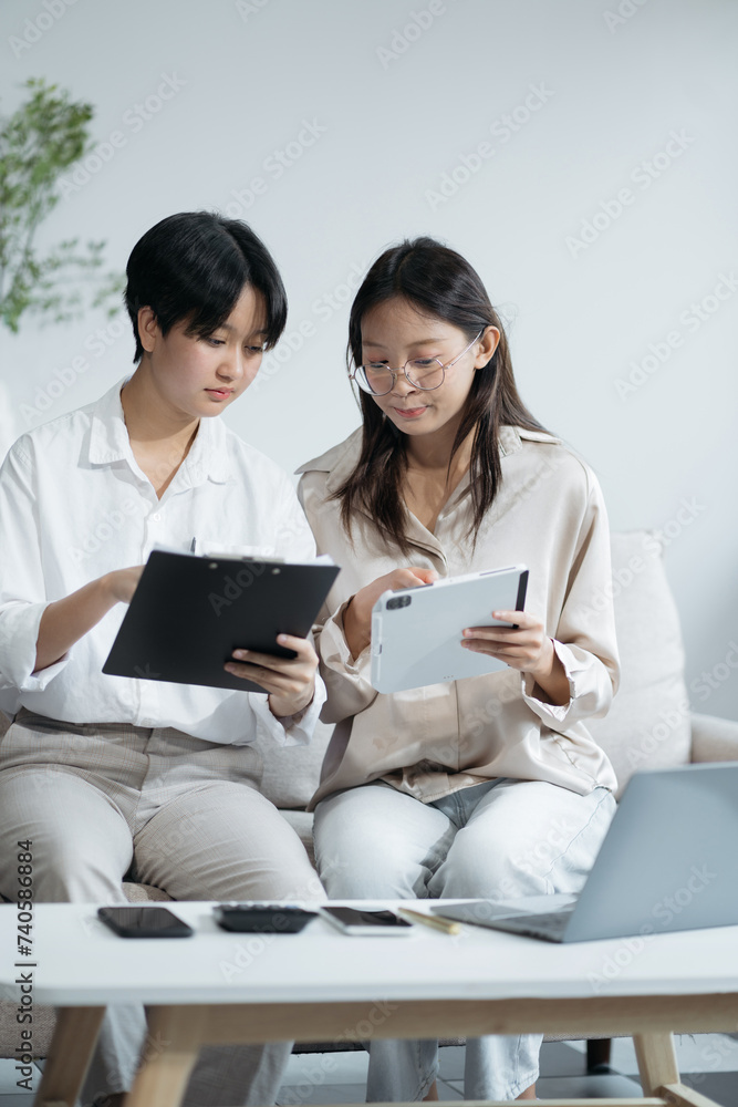 Happy lesbian couple at home looking at personal finances using a smartphone and tablet. Happy lesbian couple at home looking at personal finances using a smartphone and tablet.