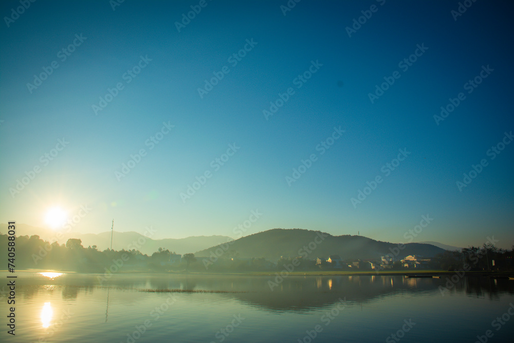 Landscape of the sun slowly rising from the mountain. Morning sunrise at Vietnam's Lak Lake.