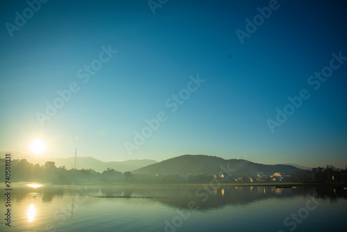 Landscape of the sun slowly rising from the mountain. Morning sunrise at Vietnam's Lak Lake. © Johnny