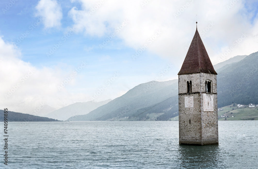 Flooded village of Resia Udine Italy. Churchtower sticking out of the water of the reservoir. Drowned village of Resia. Mountains. Nineties.