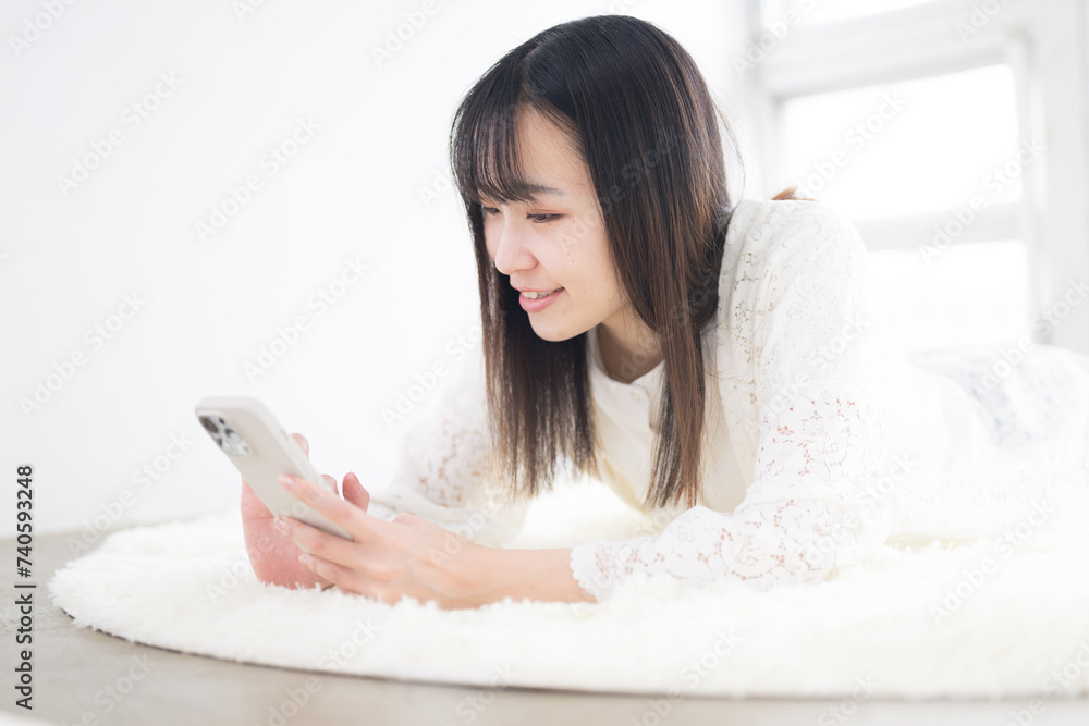 寝転がってスマホを操作する女性 横顔 寝転がってスマホを操作する女性 横顔