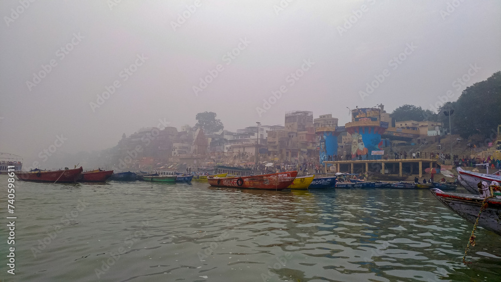 Naklejka premium VARANASI, INDIA - January 6, 2020: Boats near the Ganges river with tourists and piligrams