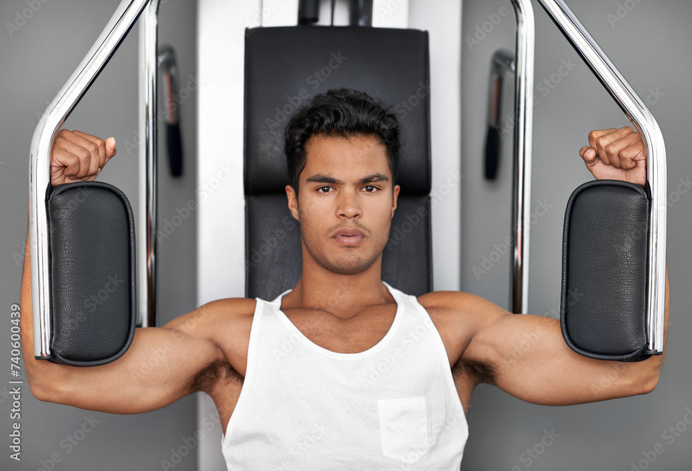 Portrait, resistance exercise and man in gym for arm muscle training for health, wellness and strength. Fitness, body and young male athlete on machine with weights for bodybuilding in sports center.