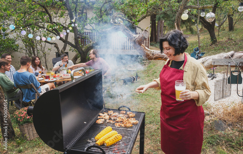 Obraz na płótnie Young happy woman in apron grilling barbecue in garden for friends at country house party w salonie