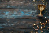 Top view of wooden background with space for text featuring golden trophy cup and streamers