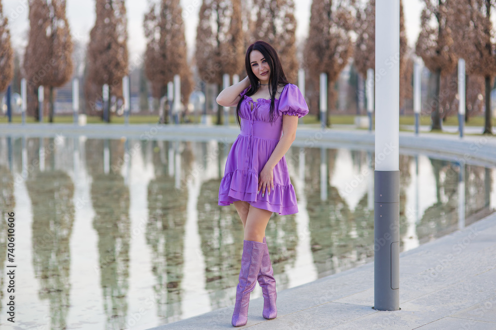 A beautiful girl student walks in the park in a sexy dress.