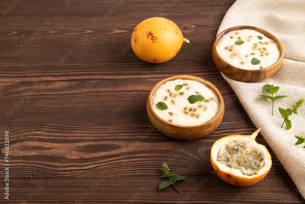 Yoghurt with granadilla and mint in wooden bowl on brown wooden, side view, copy space. Yoghurt with granadilla and mint in wooden bowl on brown wooden, side view, copy space.