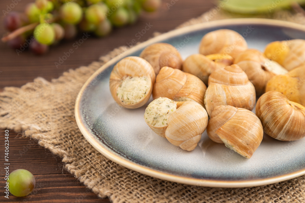 Grape (Burgundy) snails with butter and cheese on brown wooden, side view, selective focus Grape (Burgundy) snails with butter and cheese on brown wooden, side view, selective focus