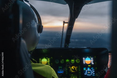 Pilot of helicopter emergency medical service flying over landscape at dusk. Themes emergency medicine, rescue, and emergency help.. photo