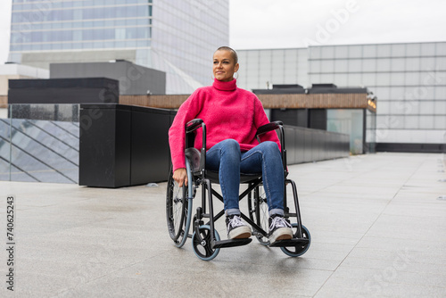 strong woman with shaved hair sitting in wheelchair © PintoArt