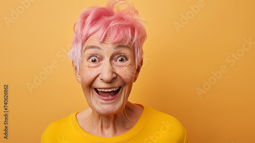 Happy smiling Elderly woman with short, pink dyed hair smiling against colorful yellow background. Vibrant and cheerful senior female portrait capturing positivity and individuality