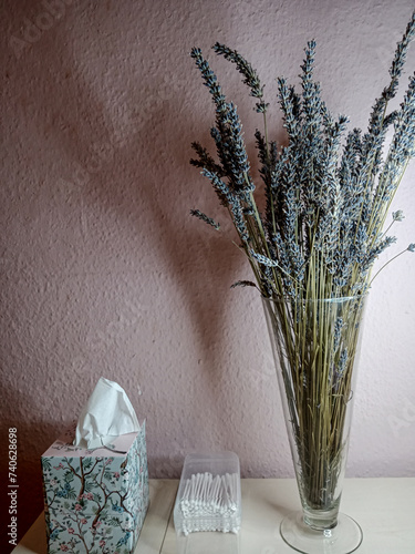 a bouquet of lavender in a glass vase on a table against a pink wall background