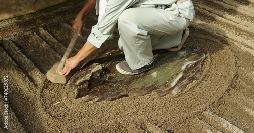 Close up of Gardener raking a Japanese Zen rock garden at Ginkakuji Temple or Silver Pavilion in Kyoto, Japan.