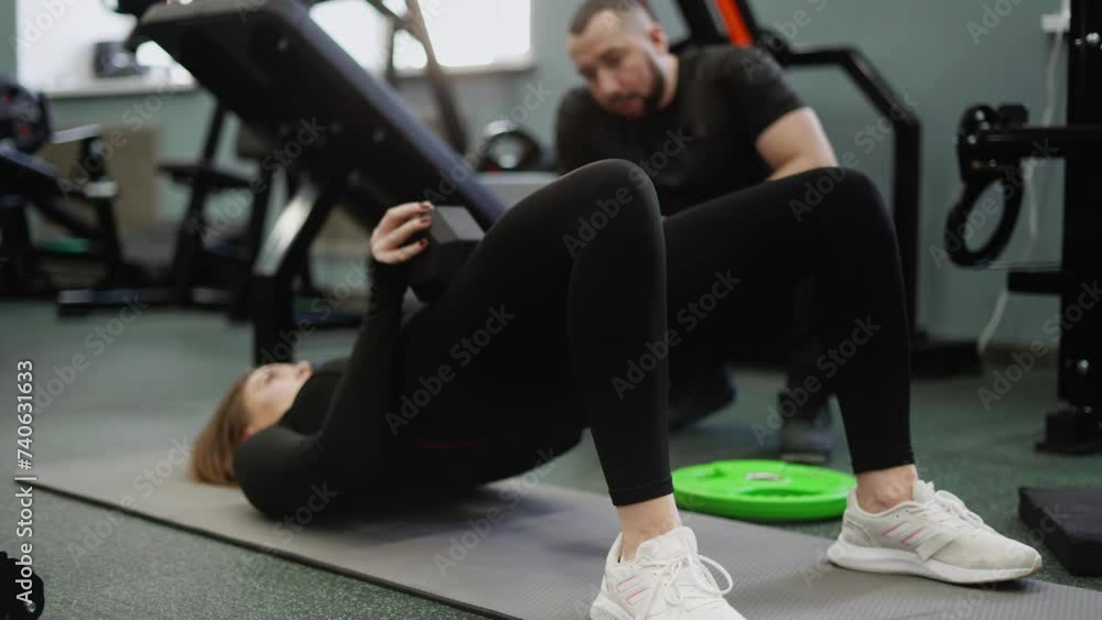 The trainer monitors and helps to perform the buttock reduction exercise correctly. Classes with an experienced coach in a gym with special equipment. The trainer monitors and helps to perform the buttock reduction exercise correctly. Classes with an experienced coach in a gym with special equipment.