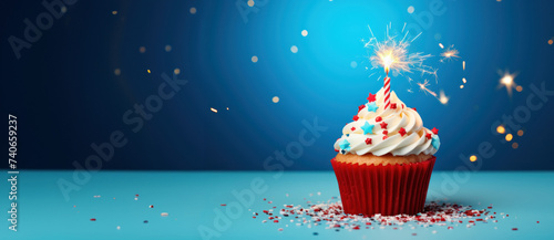 a cupcake decorated with a sparkler sitting next to blue background