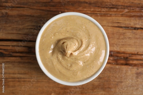 Delicious nut butter in bowl on wooden table  top view