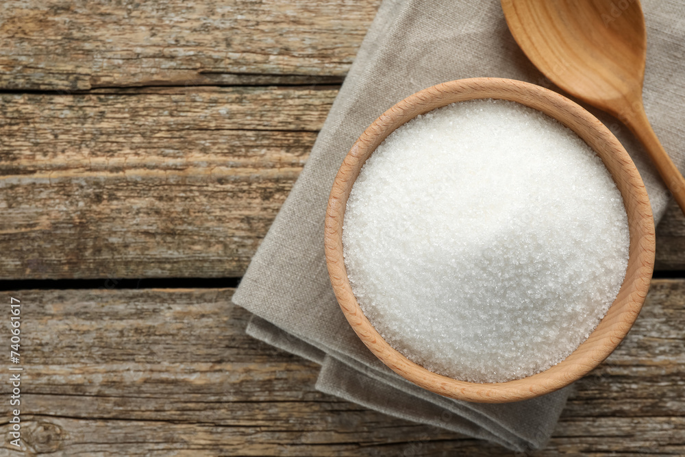 Granulated sugar in bowl and spoon on wooden table, top view. Space for text Granulated sugar in bowl and spoon on wooden table, top view. Space for text