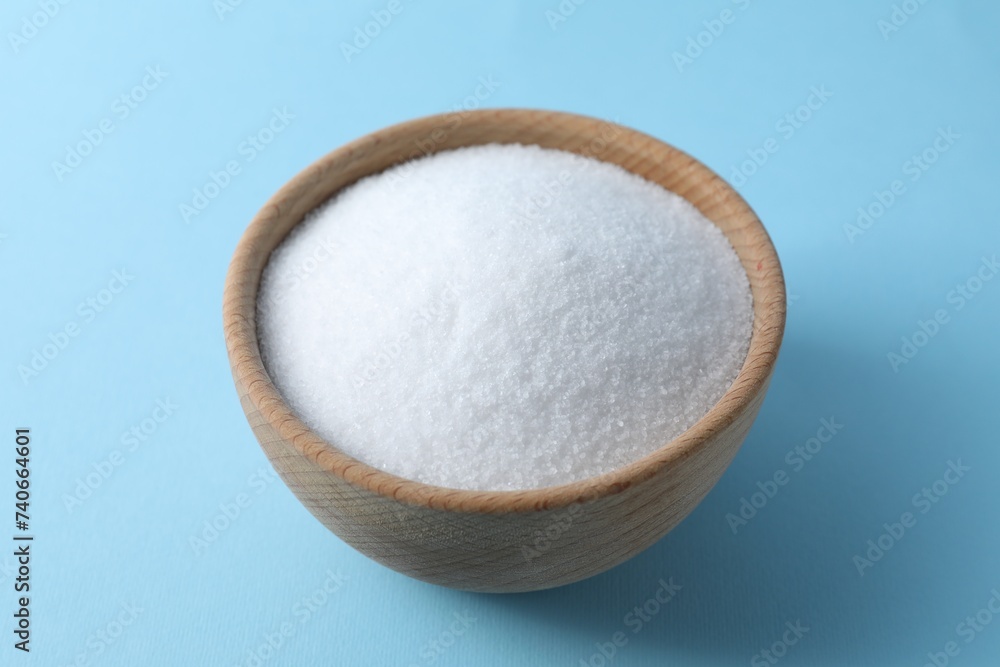 Organic white salt in bowl on light blue background Organic white salt in bowl on light blue background