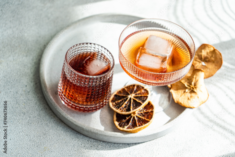 A well-lit, elegant presentation of various alcoholic drinks in ribbed glasses, accented with ice cubes and dried citrus on a circular tray A well-lit, elegant presentation of various alcoholic drinks in ribbed glasses, accented with ice cubes and dried citrus on a circular tray