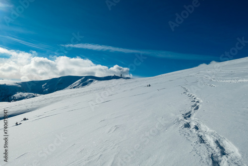 Snow shoe prints on idyllic snow covered alpine meadow with scenic view of mountain peak Grosser Speikogel in Kor Alps, Lavanttal Alps, Carinthia Styria, Austria. Winter wonderland in Austrian Alps © Chris