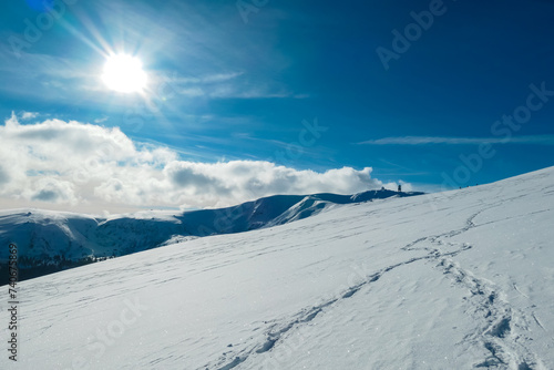 Snow shoe prints on idyllic snow covered alpine meadow with scenic view of mountain peak Grosser Speikogel in Kor Alps, Lavanttal Alps, Carinthia Styria, Austria. Winter wonderland in Austrian Alps © Chris