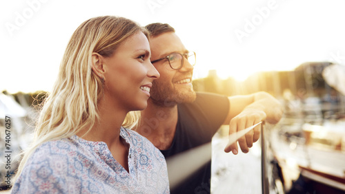 a smiling couple looks out over the horizon at sunset