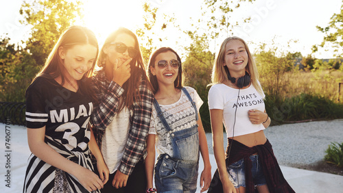 Four girls having fun together while they walk outdoors in the sunset