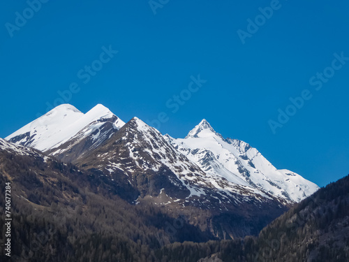 Scenic view on snow covered mountain peak Grossglockner seen from Heiligenblut, Carinthia, Austria. Tranquil serene atmosphere. Idyllic landscape in remote Austrian Alps in spring. Blue sky. Escapism