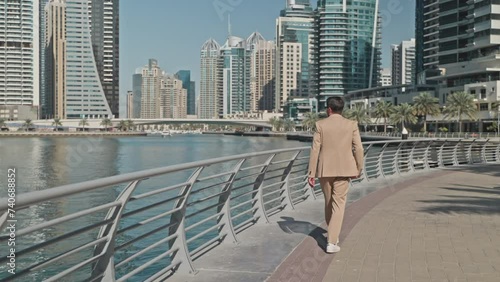 Businessman walks in dowtown on waterfront in modern megapolis in UAE. photo