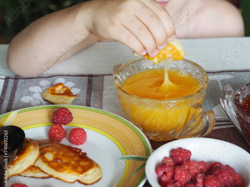 Summer children is breakfast. The child eats pancakes with honey with his hands. Baby food and allergies.