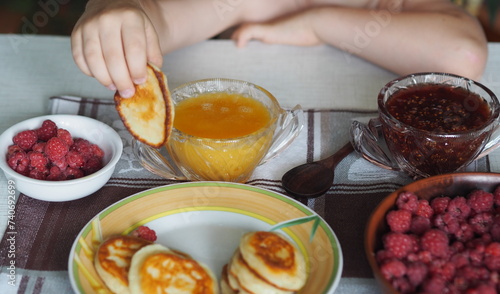Summer children is breakfast. The child eats pancakes with honey with his hands. Baby food and allergies.