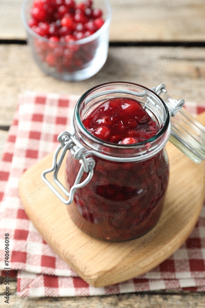 Fresh cranberry sauce in glass jar on light wooden table Fresh cranberry sauce in glass jar on light wooden table