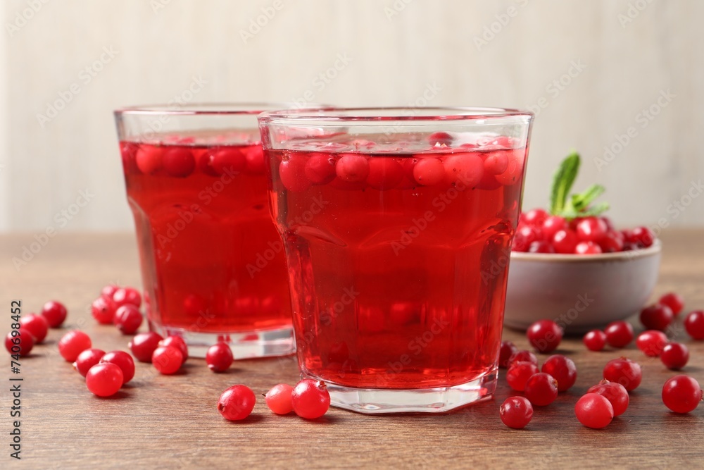 Tasty cranberry juice in glasses and fresh berries on wooden table, closeup Tasty cranberry juice in glasses and fresh berries on wooden table, closeup