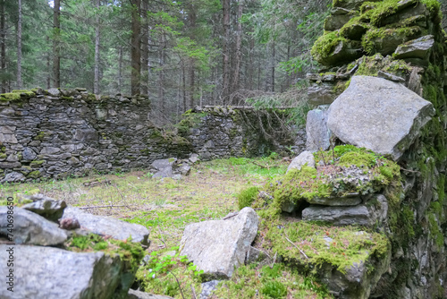 Close up view of stone ruins of medieval building in dense forest in Mur Valley, Lavanttal Alps, Styria, Austria. Misty atmosphere in remote Austrian Alps. Decayed walls are overgrown with green moss