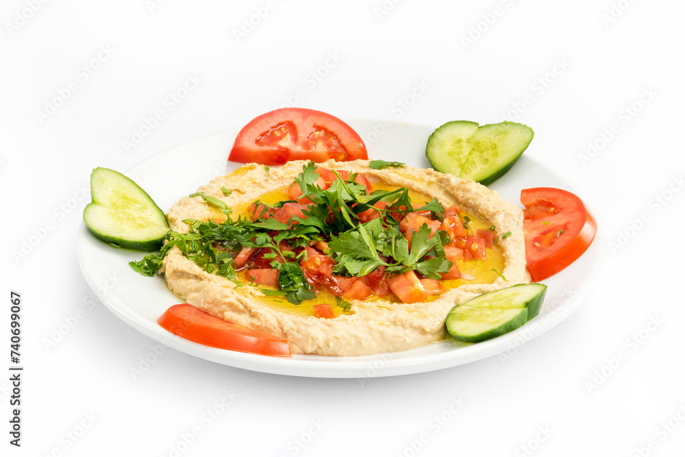 Top view of arabic mezze hummus served with fresh parsley, sliced tomatoes and cucumber. The ingredients of hummus are chickpeas, tahini and various spices.