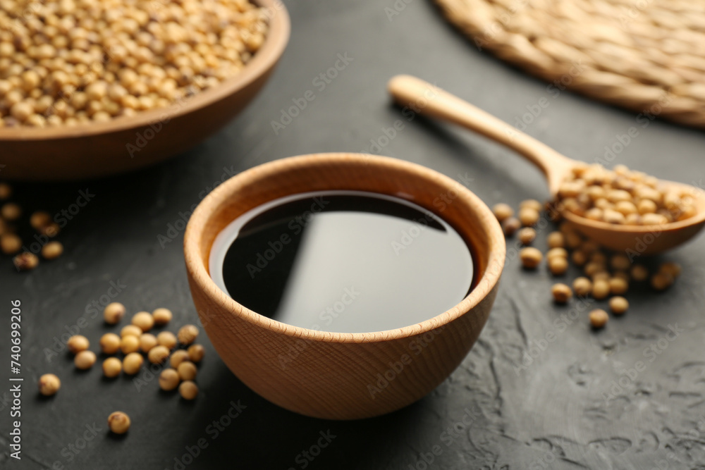 Tasty soy sauce in bowl and soybeans on black table, closeup Tasty soy sauce in bowl and soybeans on black table, closeup