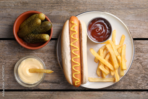 Flat lay composition with delicious hot dog and French fries on wooden table