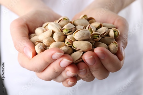 Woman holding handful of tasty pistachios, closeup photo