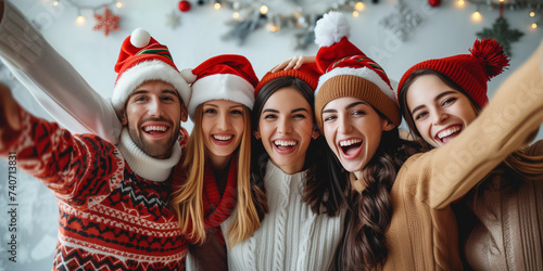 Christmas people on party. Joyful friends in Santa hats sharing a festive Christmas selfie, embodying holiday cheer and friendship