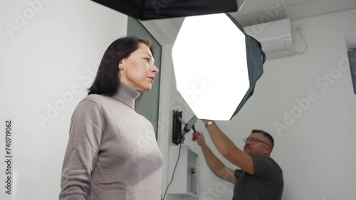 Woman posing, male dentist preparing lighting equipment to taking photo of patient in the modern dental clinic. Taking photo of female patient before whitening procedure. Cosmetic dentistry. photo
