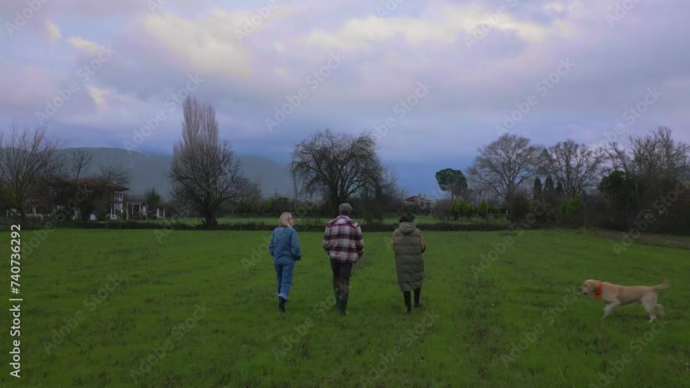 Tracking shot of friends walking in the green fields of a farm house Tracking shot of friends walking in the green fields of a farm house