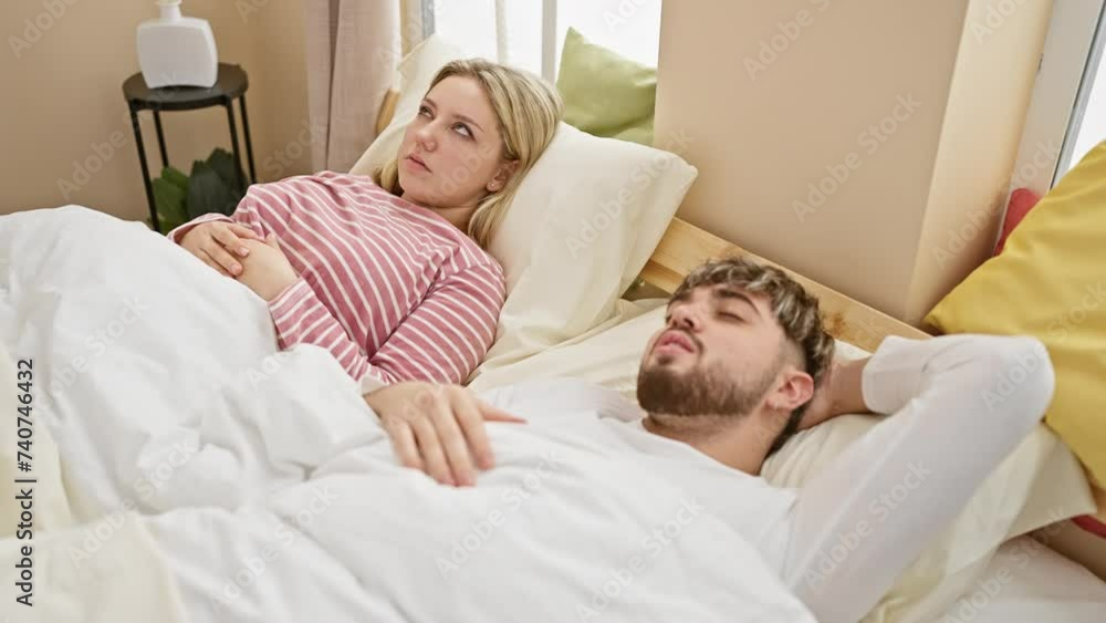 Awake woman annoyed by snoring man in a cozy bedroom setting, reflecting couple sleep issues. Awake woman annoyed by snoring man in a cozy bedroom setting, reflecting couple sleep issues.